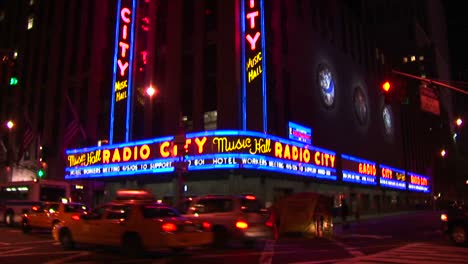 The-Camera-Pans-Down-The-Radio-City-Music-Hall-Signs-And-Marquee-To-Street-Level-With-Taxis-And-Pedestrians-In-A-Night-Shot