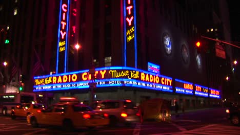 La-Cámara-Recorre-Los-Letreros-Y-La-Marquesina-De-Radio-City-Música-Hall-Hasta-El-Nivel-De-La-Calle-Con-Taxis-Y-Peatones-En-Una-Toma-Nocturna