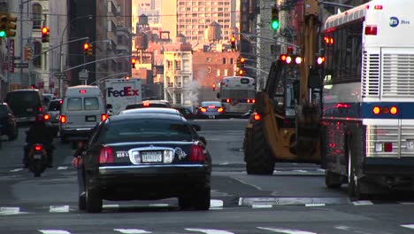 A-New-York-City-Street-Scene-With-Heavy-Traffic-Pedestrians-And-Buildings-In-The-Distance