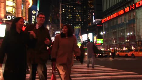 Mittlere-Aufnahme-Von-Leuten,-Die-Nachts-Durch-Den-Times-Square-Gehen