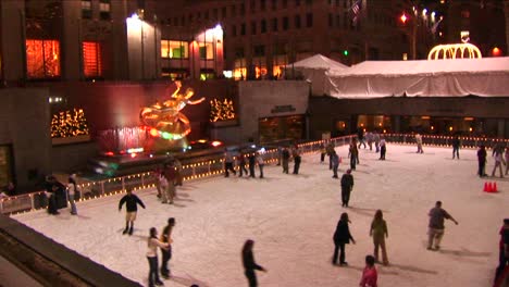 Die-Kamera-Zeigt-Skater-Nachts-Auf-Der-Rockefeller-Center-Eisbahn-Und-Schwenkt-Dann-Das-Ge-Gebäude-Hoch