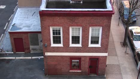 Die-Kamera-Blickt-Auf-Ein-Kleines-älteres-Zweistöckiges-Gebäude-Und-Die-Fenster-Im-Zweiten-Stock-Und-Zoomt-Dann-Hinein
