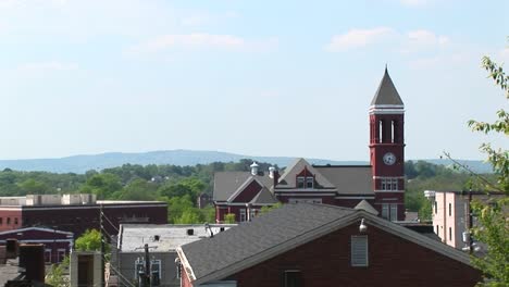 The-Camera-Pansright-Across-The-Roofline-Of-A-Small-Town-To-Highlight-An-Old-Clock-Tower