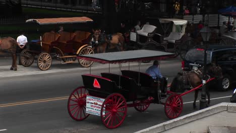 Muledrawn-Buggies-Wait-For-Tourists-While-Another-Buggy-Makes-Its-Way-Down-A-Crowded-Street-In-New-Orleans