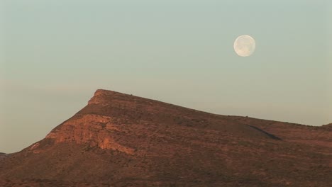 Mediumshot-Of-The-Moon-Hovering-Over-A-Rocky-Landscape