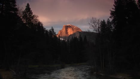 Mittlere-Aufnahme-Des-Fließenden-Mercedes-Flusses-Mit-Strahlender-Halber-Kuppel-Des-Yosemite-Nationalparks-Im-Hintergrund