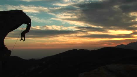 Panlinks-Eines-Silhouettierten-Kletterers,-Der-Von-Einer-überhängenden-Felswand-Mit-Kalifornien-Sonnenuntergang-Darüber-Hängt
