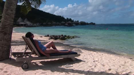 A-woman-relaxes-on-a-beach-chair-on-a-tropical-beach