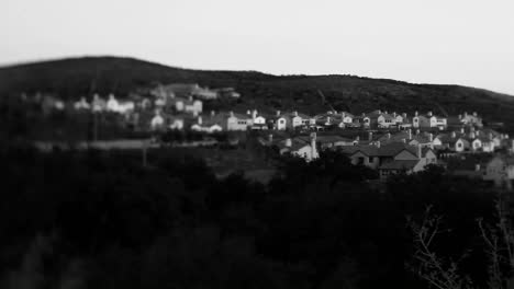 Black-and-white-shot-of-tract-homes-behind-a-for-sale-in-an-upscale-urban-neighborhood-at-dusk