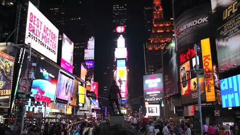 Tilt-down-shot-of-Times-Square-lit-up-and-crowded-at-night