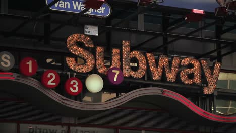 A-lit-up-subway-sign-sparkles-above-a-busy-street-in-New-York-City