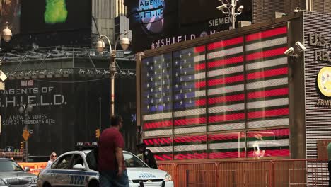Fußgänger-Passieren-Vor-Einer-Beleuchteten-Amerikanischen-Flagge-Auf-Einer-Belebten-Straße-In-New-York-City