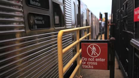 Ein-Zug-Fährt-Aus-Einem-Bahnhof-In-New-York-City-Neben-Einem-Schild,-Das-Reisende-Davor-Warnt,-Die-Gleise-Zu-Betreten-Oder-Zu-überqueren