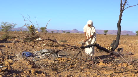An-old-Moroccan-man-chops-wood-in-the-desert