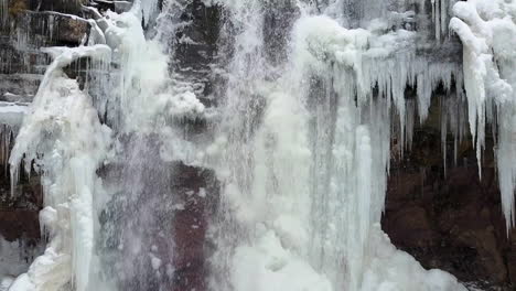 Beautiful-rising-winter-aerial-of-a-high-waterfall-in-a-frozen-landscape-1
