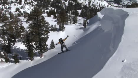 Siguiente-Toma-De-Un-Snowboarder-Saltar-De-Una-Pendiente-Y-Aterrizar-En-Polvo-Profundo