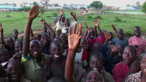 Mittlere-Aufnahme-Einer-Gruppe-Von-Kindern-In-Einem-Flüchtlingslager-In-Uganda,-Die-In-Die-Kamera-Winkt