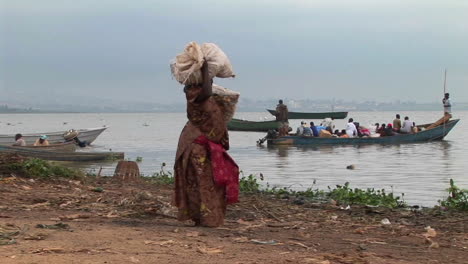 Panright-De-Una-Mujer-Muy-Cargada-Que-Llevaba-Paquetes-A-Un-Barco-De-Pesca-En-Las-Orillas-Del-Lago-Victoria