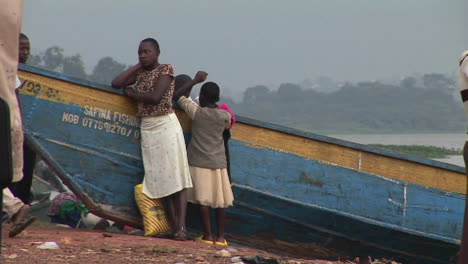 Mediumshot-of-a-woman-and-children-leaning-against-a-boat-on-the-shores-of-Lake-Victoria