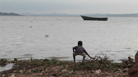 Mediumshot-of-a-young-boy-playing-on-the-shore-of-Lake-Victoria-Uganda