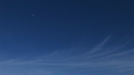 Wurmblick-Auf-Einen-Blauen-Himmel-Mit-Wolkenfetzen-Und-Einem-Fernen-Mond