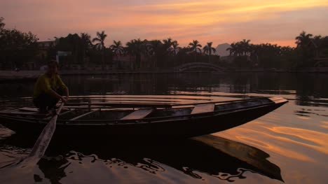 Dame-Auf-Einem-Traditionellen-Vietnamesischen-Boot-Bei-Sonnenuntergang