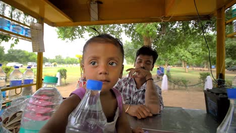 Indian-Toddler-Reaches-Through-Water-Bottles