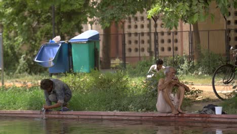 Hombres-indios-se-lavan-los-pies-junto-a-un-estanque
