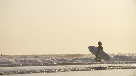Hombre-llevando-una-tabla-de-surf-al-mar