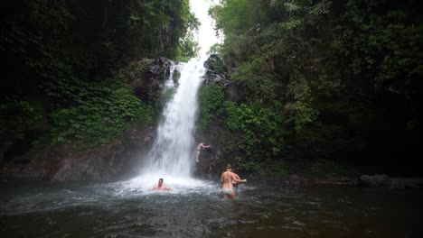 Reveal-Shot-of-Swimmers-Under-a-Waterfall