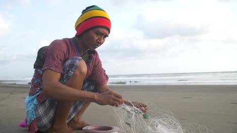 Hombre-desenredando-una-red-de-pesca-en-una-playa
