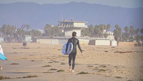 Man-in-Wetsuit-Holding-Surfboard