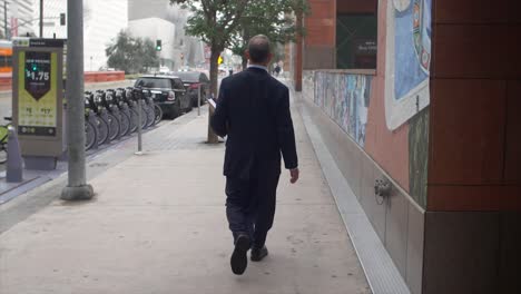 Businessman-Walking-On-Pavement