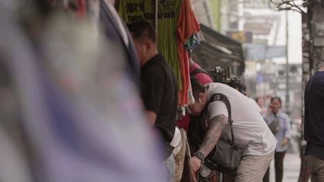 Hombre-examinando-ropa-en-el-puesto-de-Bangkok