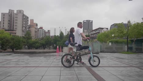 Hombre-y-mujer-caminando-con-bicicleta-Taipei