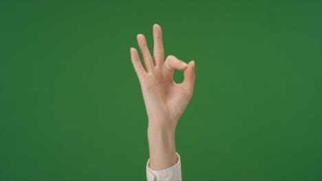 Female-hand-making-OK-gesture-on-green-screen