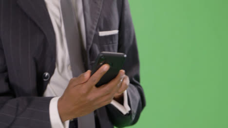 CU-Texting-Businessman-walking-towards-camera-on-green-screen