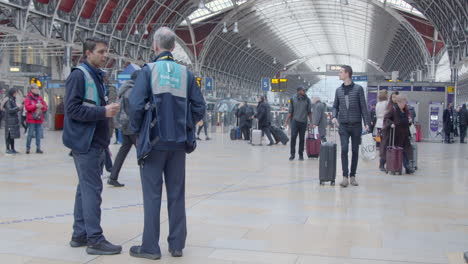 Two-train-stewards-stands-as-people-pass-through-station