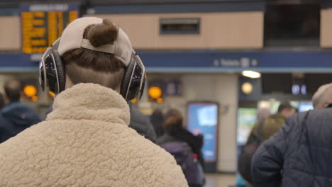 Man-wearing-headphones-in-crowded-train-station