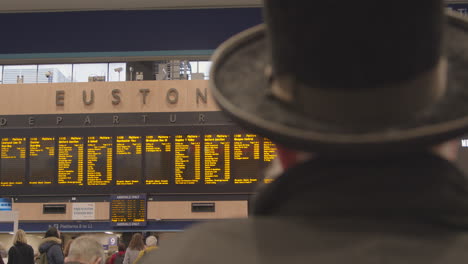 Mann-Mit-Hut,-Der-Auf-Die-Abfahrtstafel-Des-Bahnhofs-Euston-Schaut