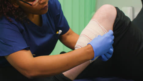 Cu-Krankenschwester-Beendet-Das-Verbinden-Des-Verletzten-Beins