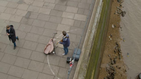 Overhead-of-Street-Musician-And-Passing-Pedestrian