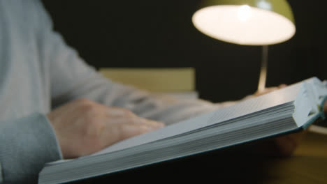 Male-Holding-and-Reading-Book-with-Book-Stack