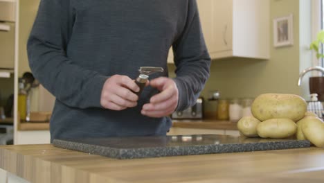 Man-Starts-to-Peel-Potatoes-in-Kitchen