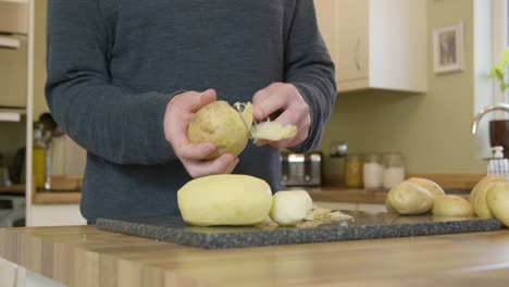 Hombre-Pelar-Patatas-En-La-Cocina