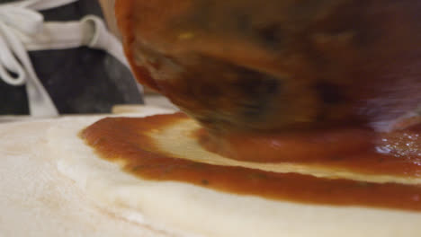 Close-Up-Spreading-Tomato-Sauce-on-Pizza-Dough