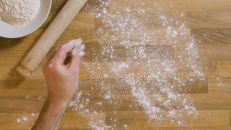 Top-View-Male-Sprinkling-Flour-on-Worktop