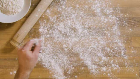 Top-View-Male-Sprinkles-Flour-on-Worktop