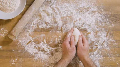 Top-View-Male-Sprinkles-Flour-on-Dough-and-Worktop-