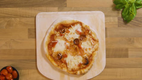 Top-View-Cooked-Pizza-on-Peel-Placed-on-Worktop
